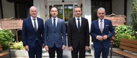 Mężczyźni pozujący do zdjęcia. stoją przed budynkiem w garniturach.
