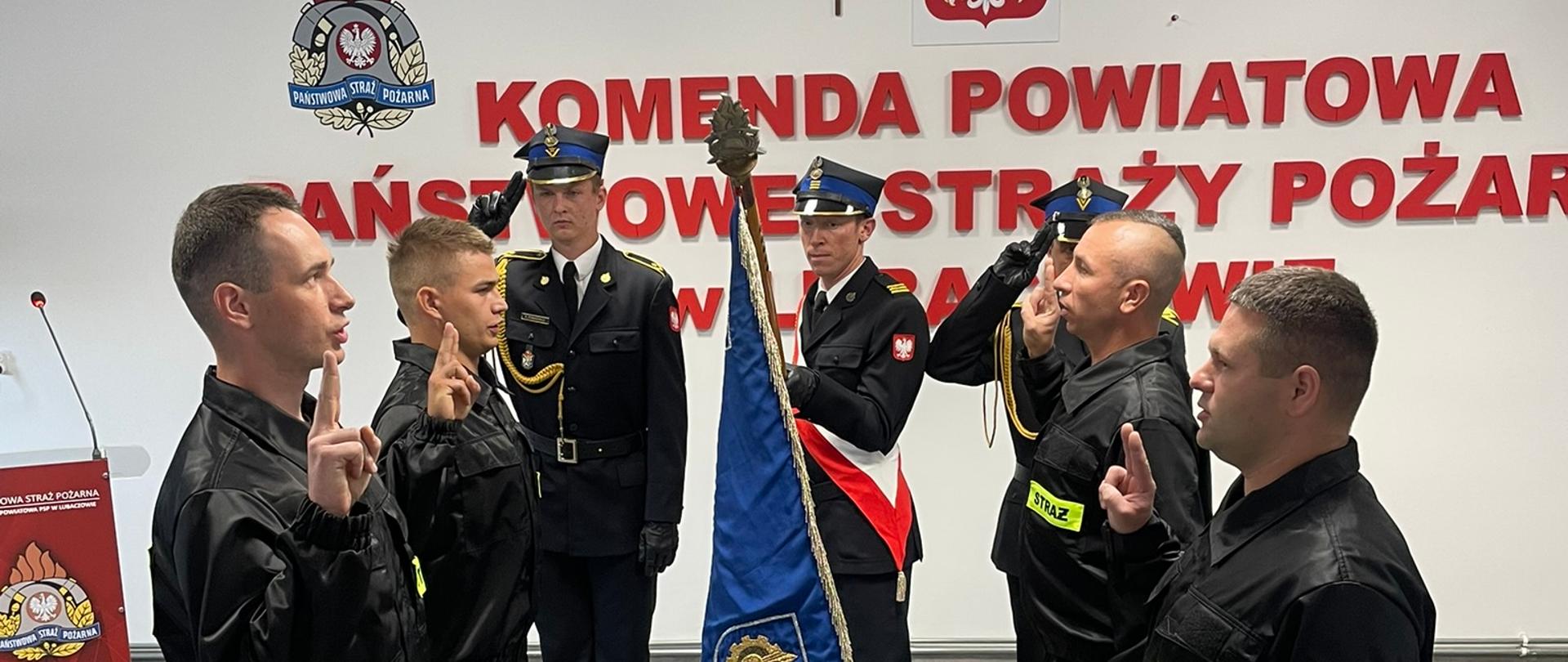 Zdjęcie przedstawia strażaków w ubraniu koszarowym, podczas ślubowania na sztandar.