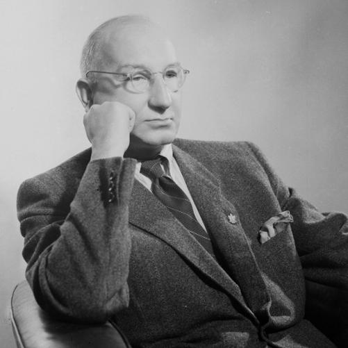 Wincenty Rzymowski - portret łysiejącego mężczyzny w okularach, siedzącego na fotelu, podpierającego pięścią twarz. Ciemna marynarka, ciemny krawat, biała koszula.