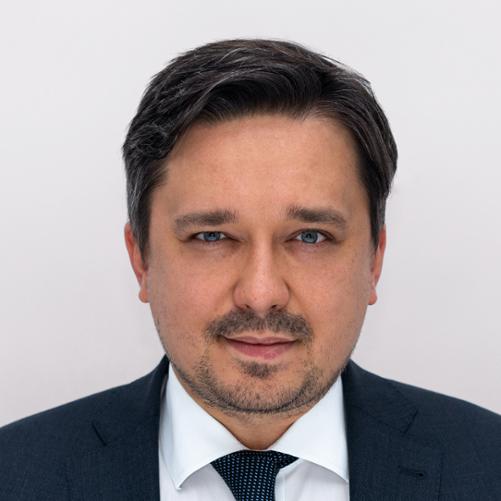 Portret Marcina Wiącka - uśmiechnięty mężczyzna w garniturze