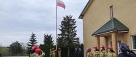 Strażacy wciągają flagę państwową na maszt.