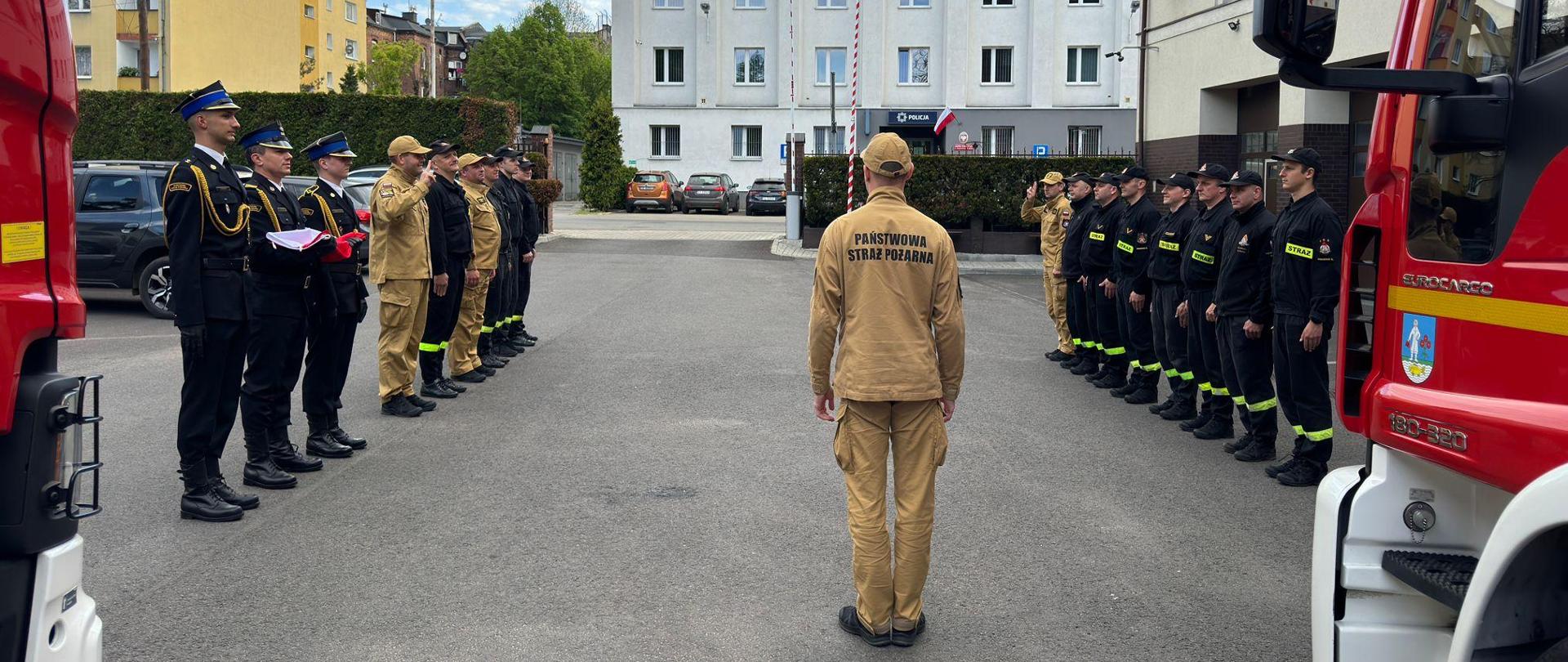 Uroczysta zmiana służby w KM PSP Siemianowice Śląskie z okazji Dnia Flagi Rzeczypospolitej Polskiej. Po lewej zmiana zdająca wraz z pocztem sztandarowym, po prawej zmiana przyjmująca.