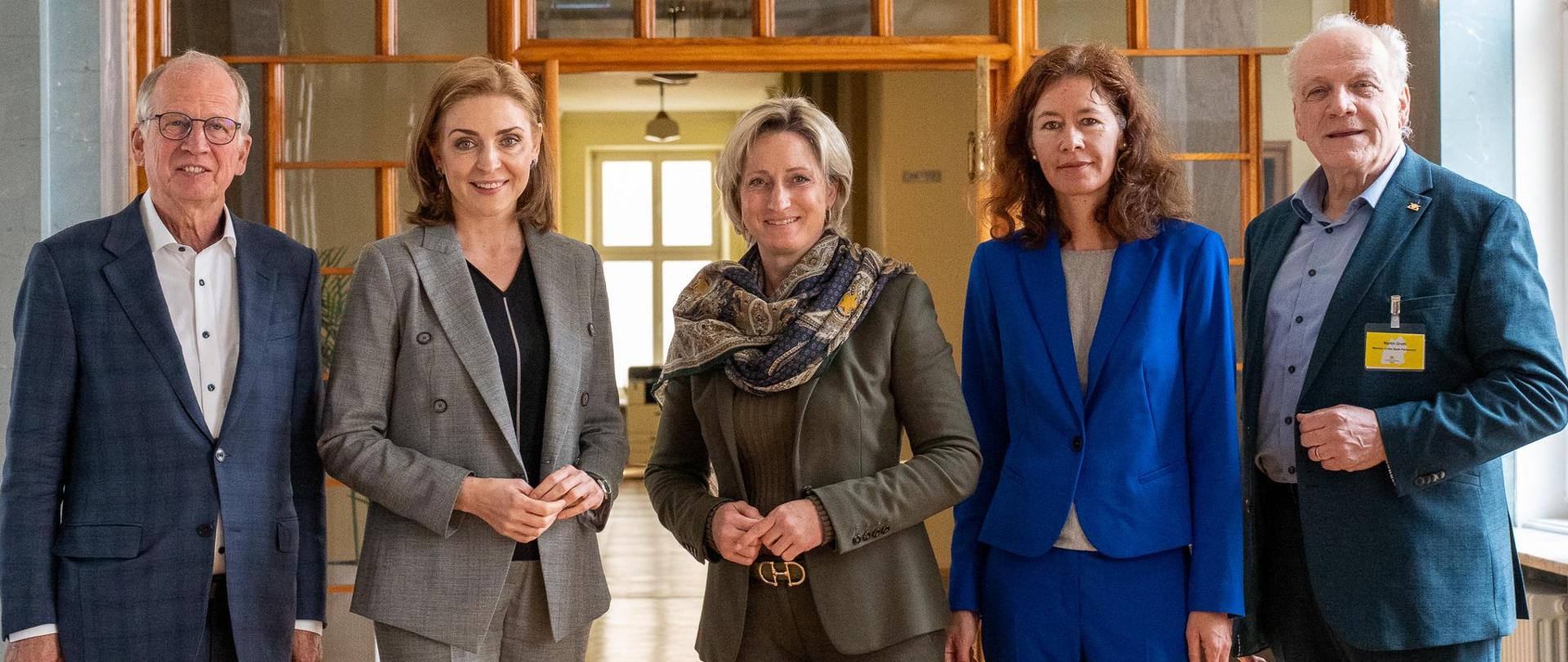 Członkowie delegacji niemieckiej stoją na korytarzu Ministerstwa Edukacji wraz z wiceminister Joanną Muchą i pozują do zdjęcia.