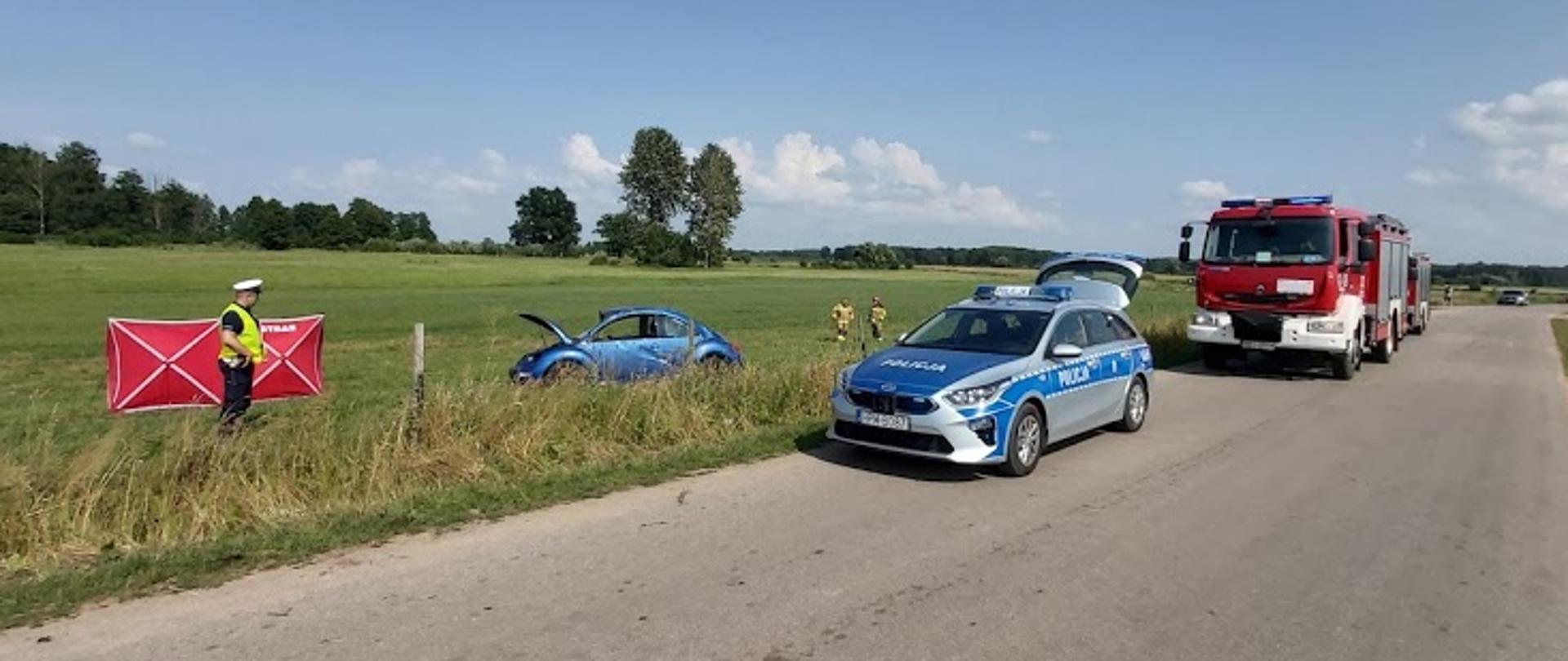 Na zdjęciu widać funkcjonariusza policji oraz wóz bojowy straży pożarnej i policji 