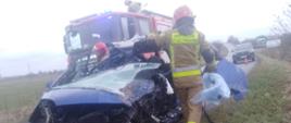 Na miejscu widoczny wrak samochodu osobowego wraz z strażakiem prowadzącym działania.