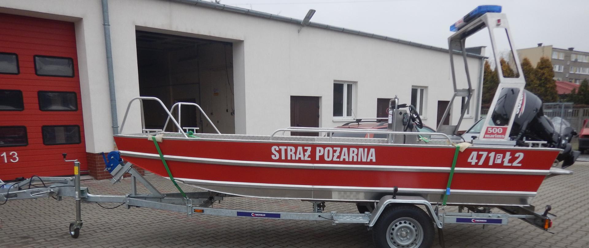 czerwona lódź z napisem straż pożarna stojąca przed budynkiem