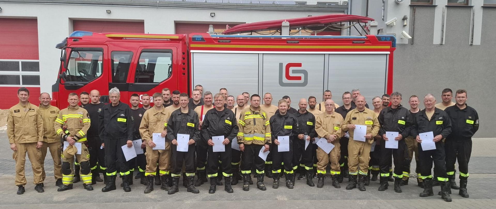 Strażacy na zdjęciu grupowym na tle samochodu