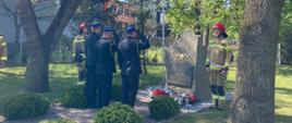 Strażacy składają wieńce pod pomnikiem pamięci strażaków. Oddają hołd zmarłym strażakom.