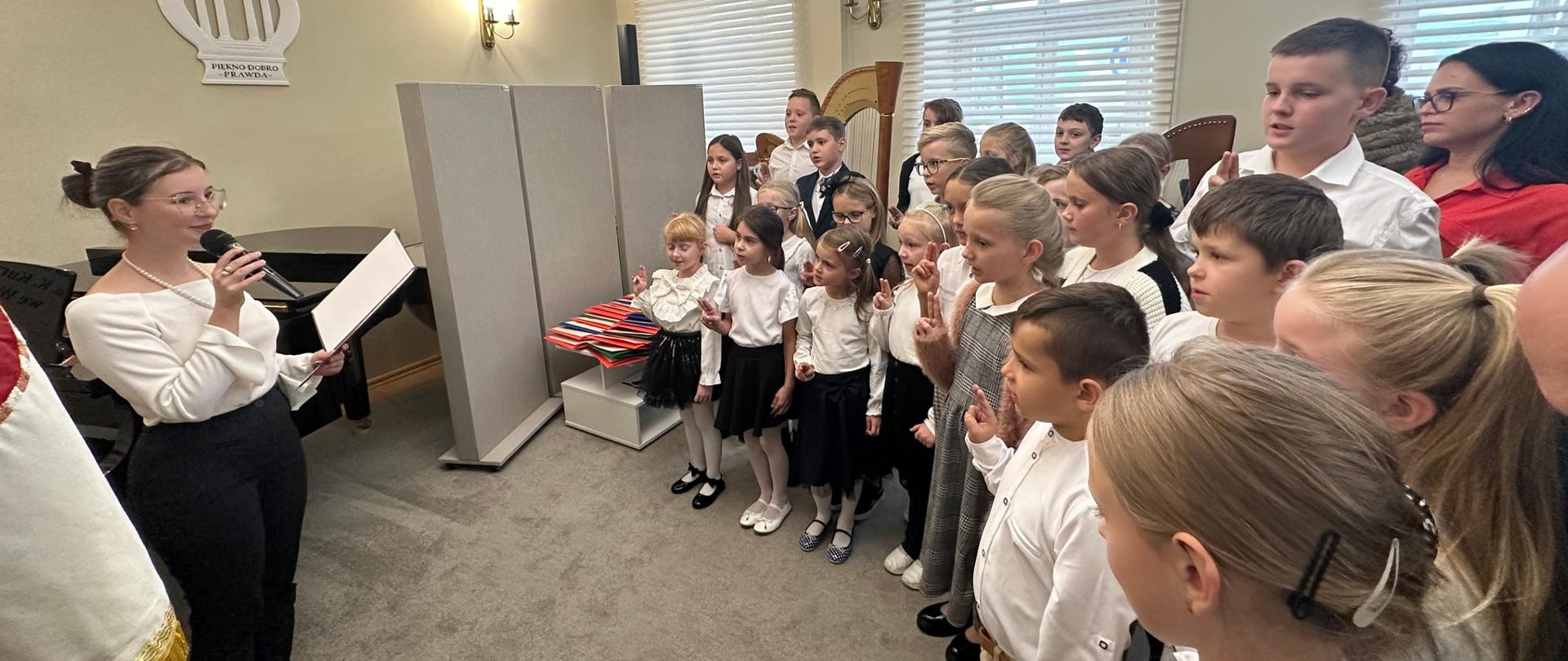 Uczniowie składający ślubowanie w auli szkoły.