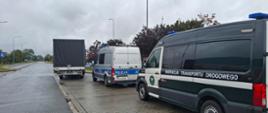 Radiowozy Policji i Inspekcji Transportu Drogowego stojące na parkingu obok zatrzymanego samochodu dostawczego