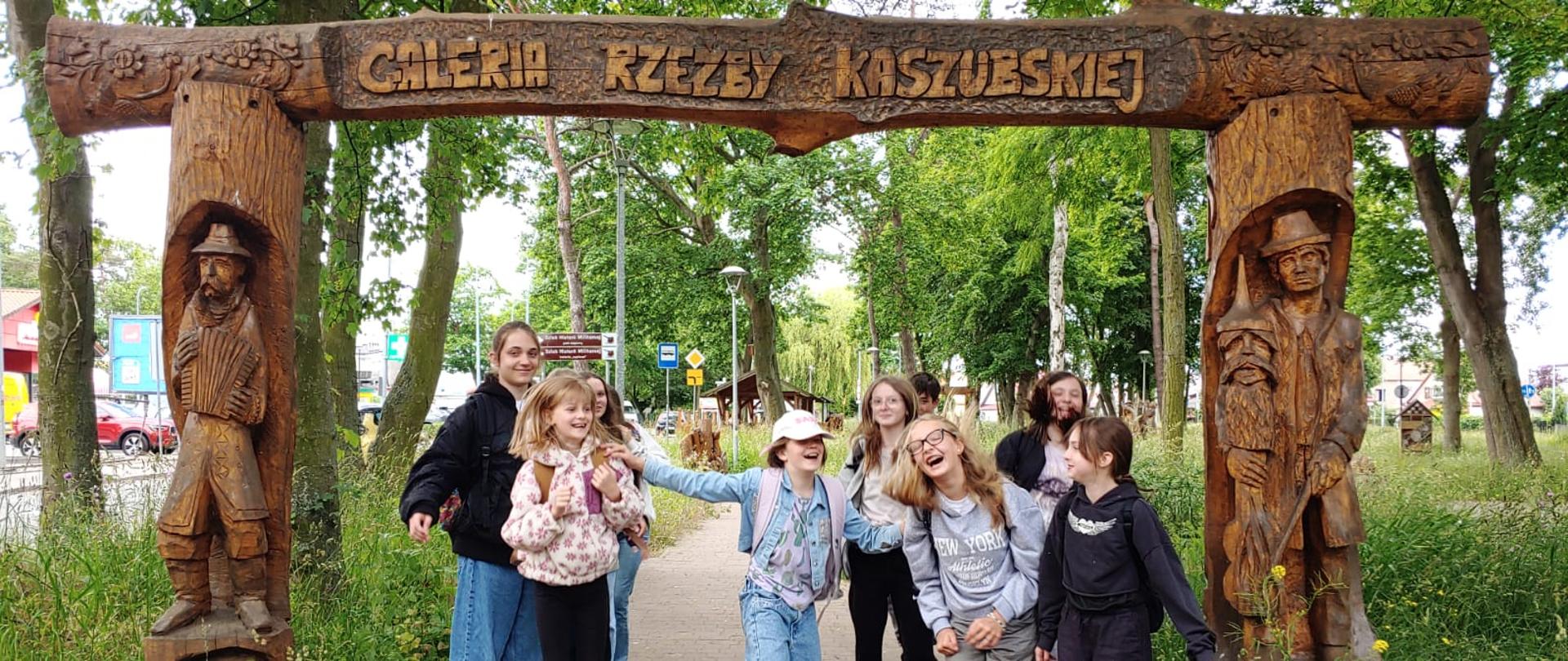 uczennice przy ozdobnej drewnianej bramie