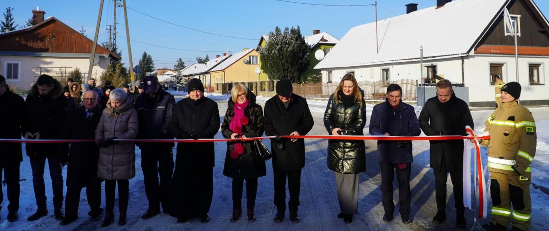 Uczestnicy uroczystości przecinają wstęgę podczas oddania do użytku inwestycji drogowej