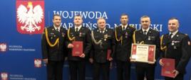 Zdjęcie przedstawia funkcjonariuszy Komendy Powiatowej Państwowej Straży Pożarnej w Gołdapi, którzy otrzymali odznaczenia, awanse i wyróżnienia podczas uroczystej zbiórki z okazji Narodowego Święta Niepodległości zorganizowanej w Warmińsko–Mazurskim Urzędzie Wojewódzkim w Olsztynie
