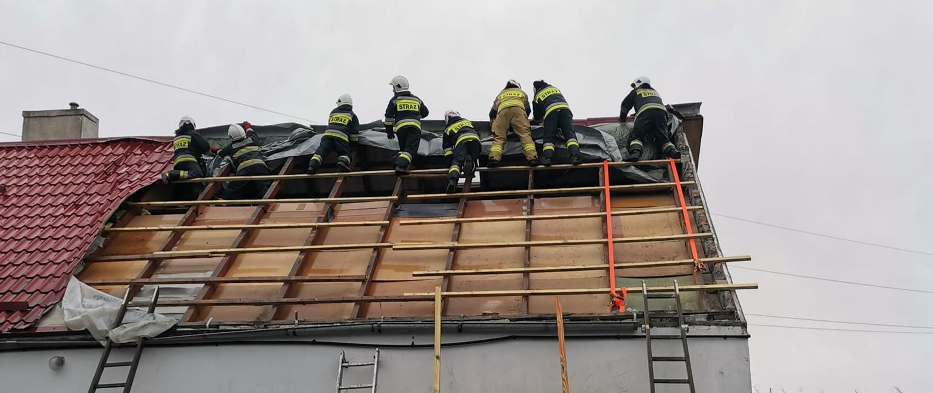 Strażacy przykrywają plandeką konstrukcję dachu