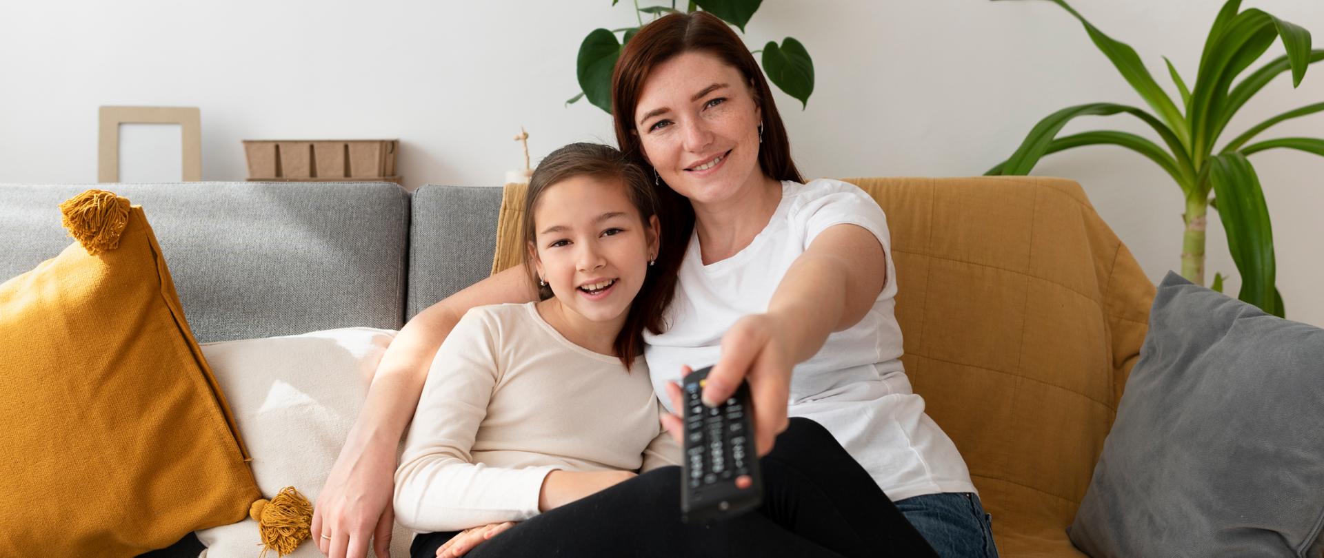 Mother with dauther sitting on couch, watching TV