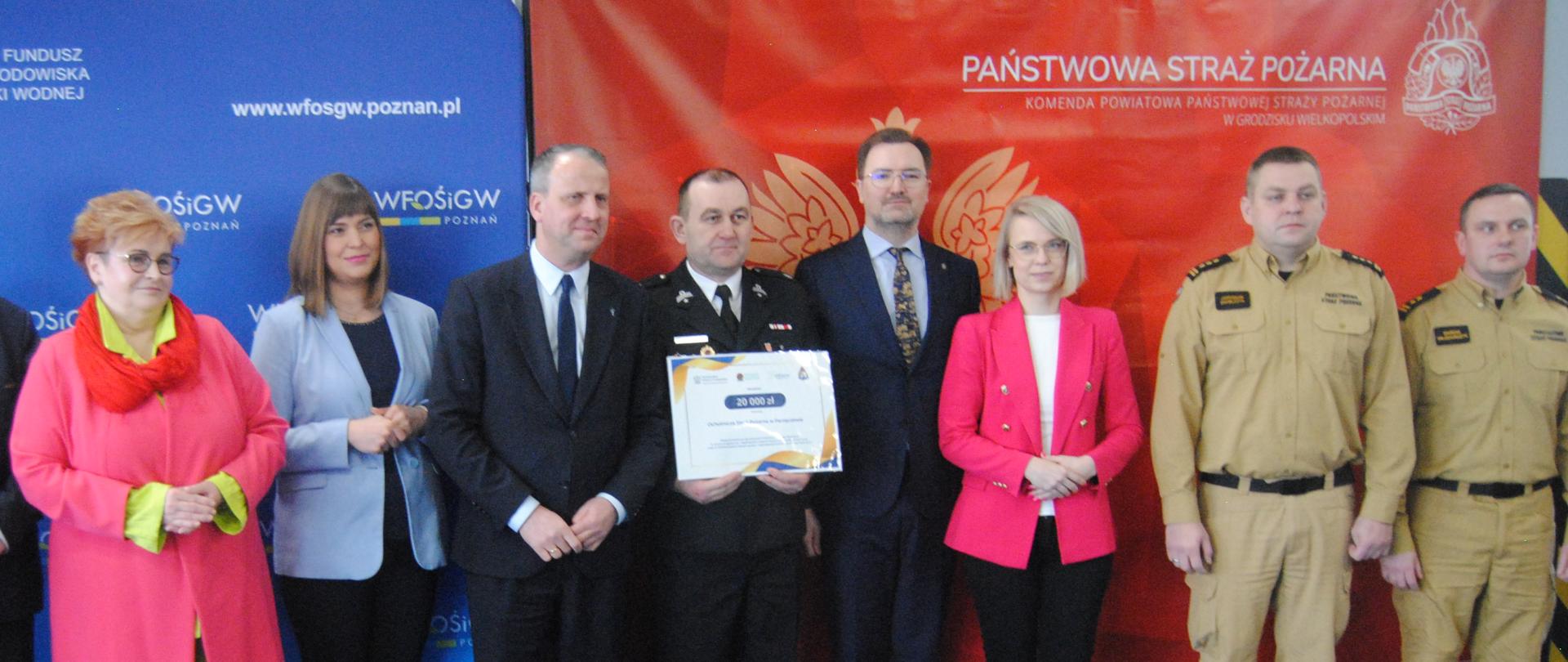 grupa ludzi stoi obok siebiue za nimi niebieska oraz czerwona ścianka tekstylna