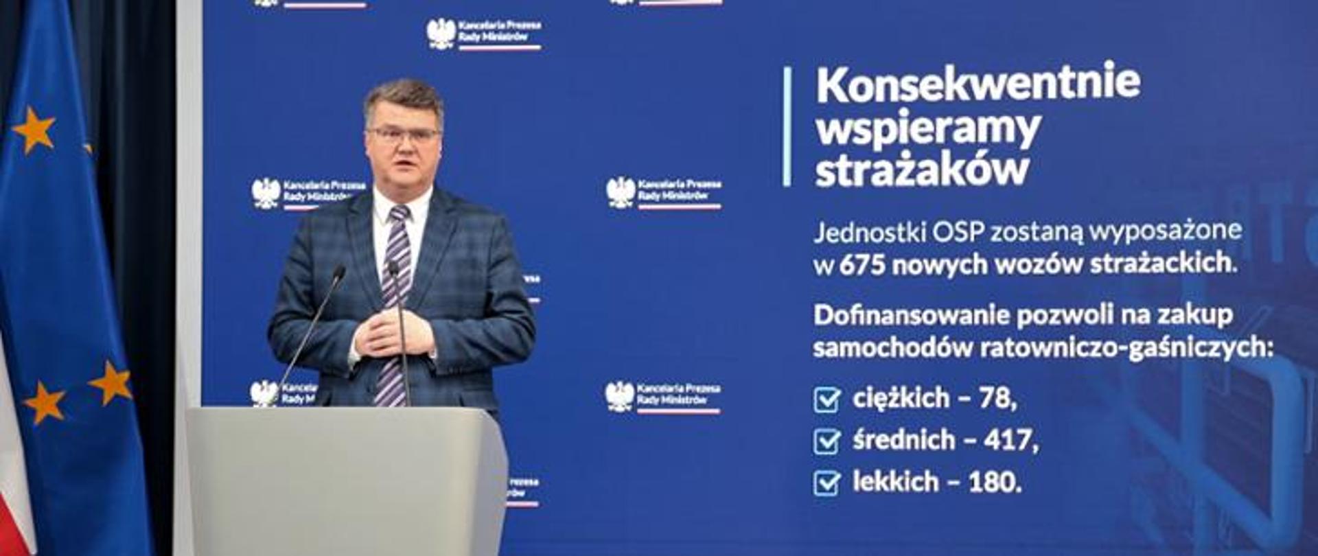 Grafika z konferencji ministra wąsika na której przedstawia na prezentacji ilość kupionych wozów strażackich w 2023 roku