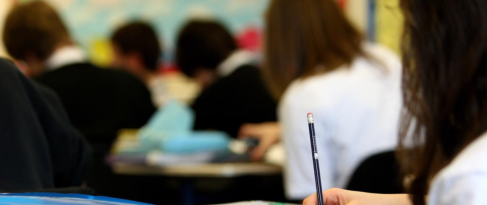 fragment biurka szkolnego z dziećmi w tle