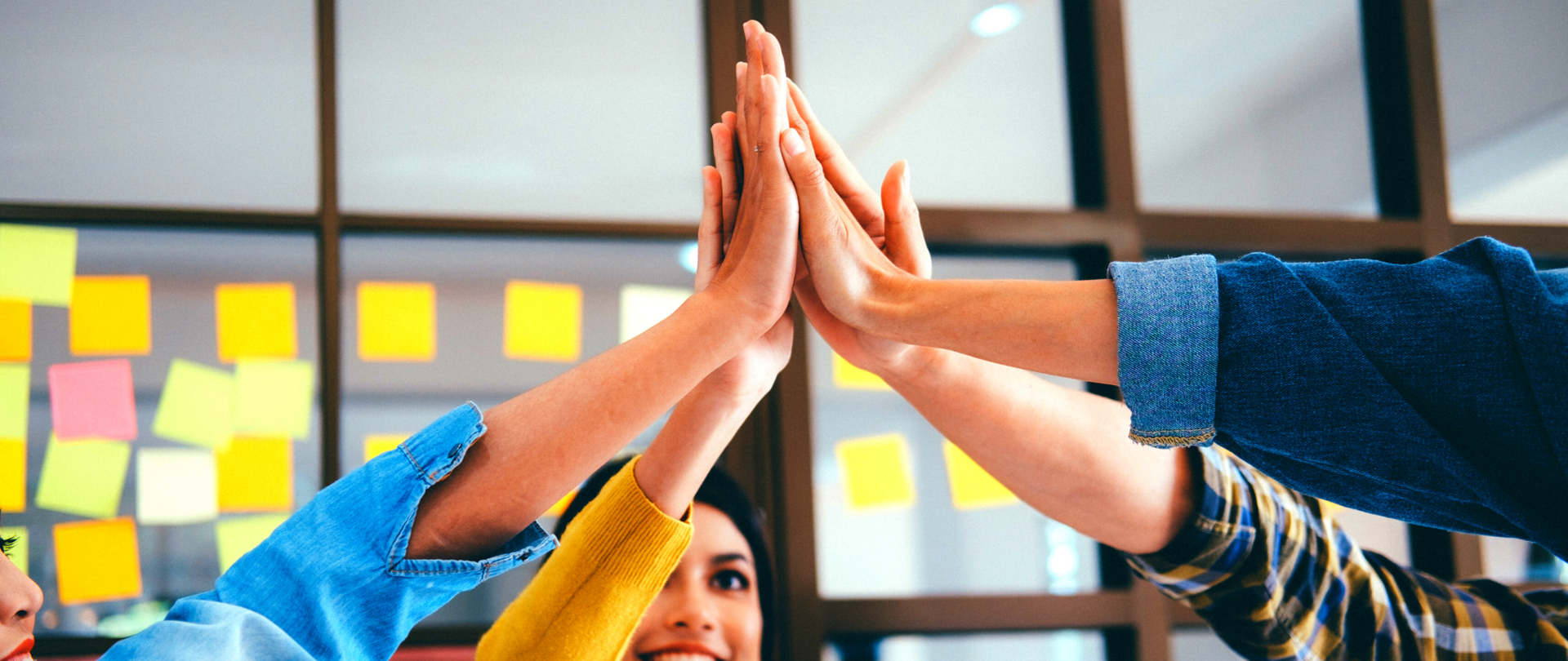 Kilka osób przybija piątkę (wysoko, nad głowami).