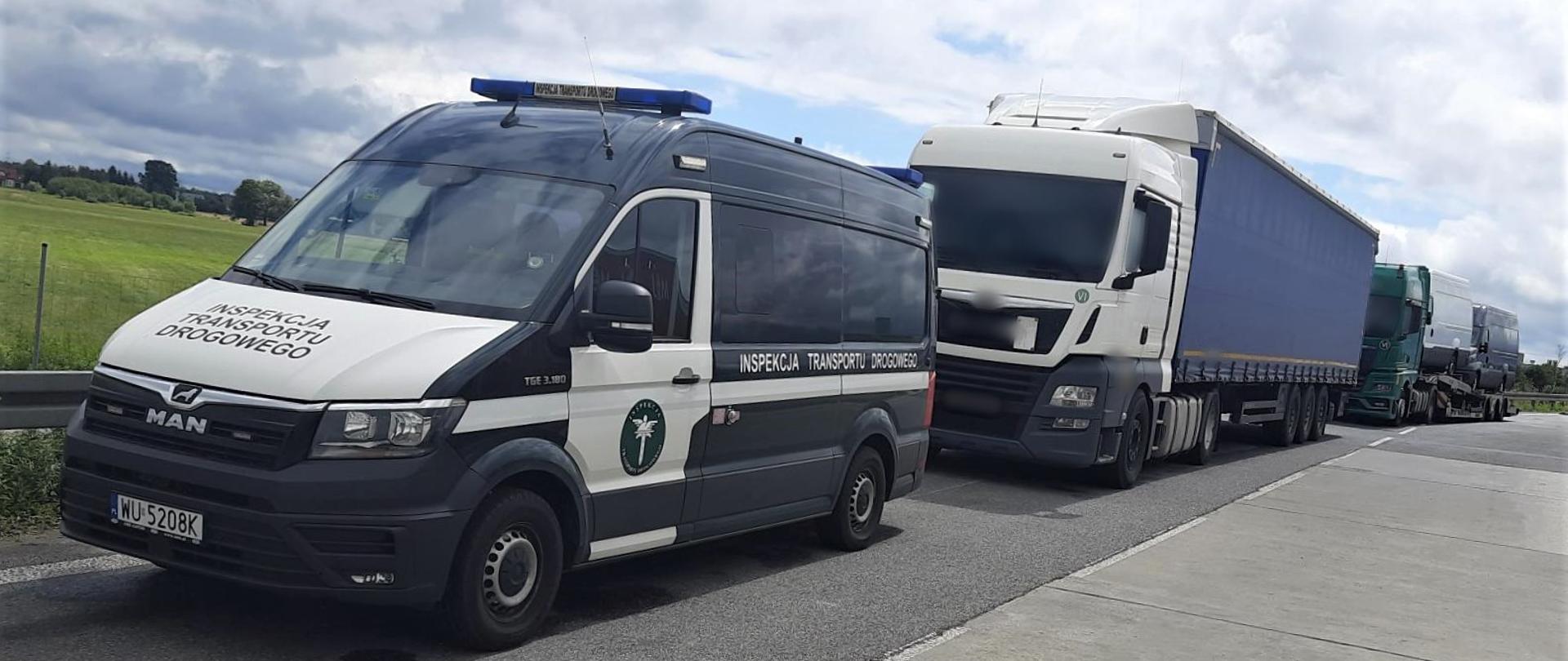 Na pierwszym planie (od lewej): oznakowany furgon mazowieckiej Inspekcji Transportu Drogowego. W tle: za inspekcyjnym radiowozem stoją dwa kontrolowane ciągniki siodłowe z podpiętymi naczepami.