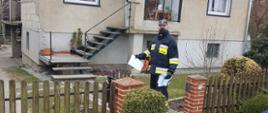 Widać strażaka z dostarczaną ulotką przy wejściu