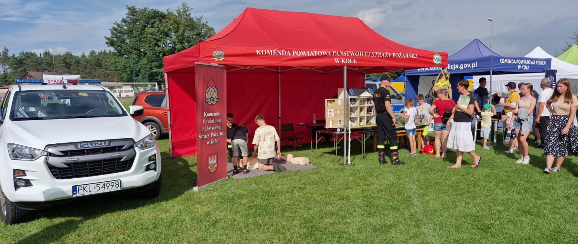 Zdjęcie przedstawia pojazd pożarniczy, interaktywny symulator edukacyjny oraz sprzęt do ćwiczenia KPP.