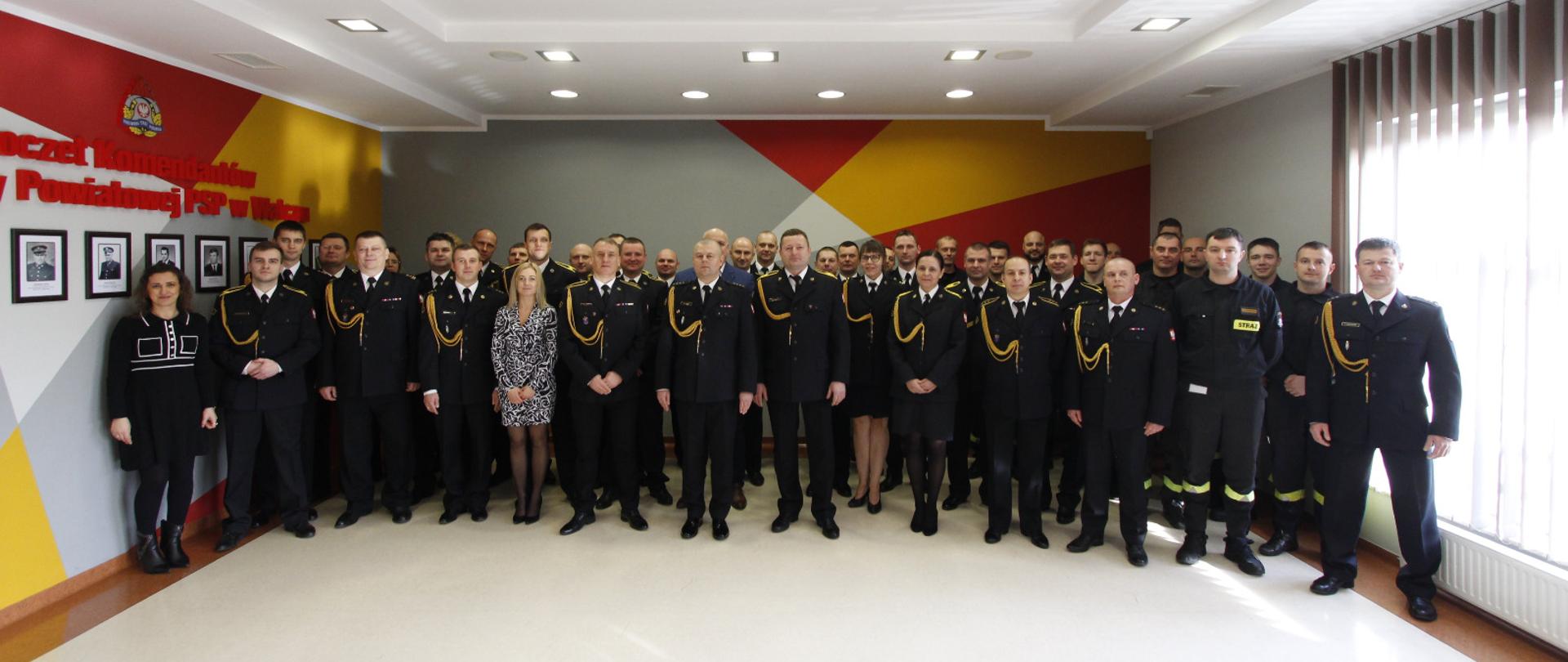 Zdjęcie przedstawia funkcjonariuszy i pracowników cywilnych KP PSP w Wałczu pozujących do wspólnego zdjęcia na sali konferencyjnej.