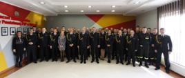 Zdjęcie przedstawia funkcjonariuszy i pracowników cywilnych KP PSP w Wałczu pozujących do wspólnego zdjęcia na sali konferencyjnej.