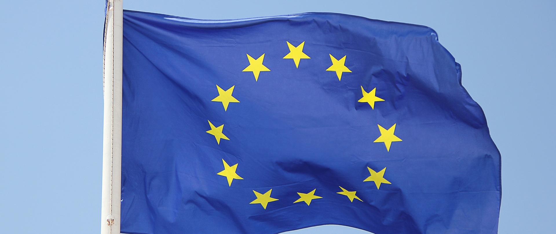 Zdjęcie przedstawia flagę Unii Europejskiej - 12 złotych gwiazd na granatowym tle