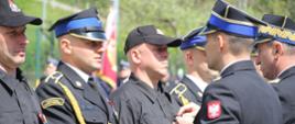 Na zdjęciu widoczni Małopolski Komendant Wojewódzki PSP i komendant powiatowy PSP w Gorlicach wręczający strażakom odznaczenia resortowe. Komendanci w galowych granatowych mundurach i w czapkach rogatywkach. Strażacy odbierający odznaczenia ubrani w galowe granatowe mundury i w czapkach rogatywkach oraz dwóch w ubraniu koszarowym koloru czarnego w czapce.