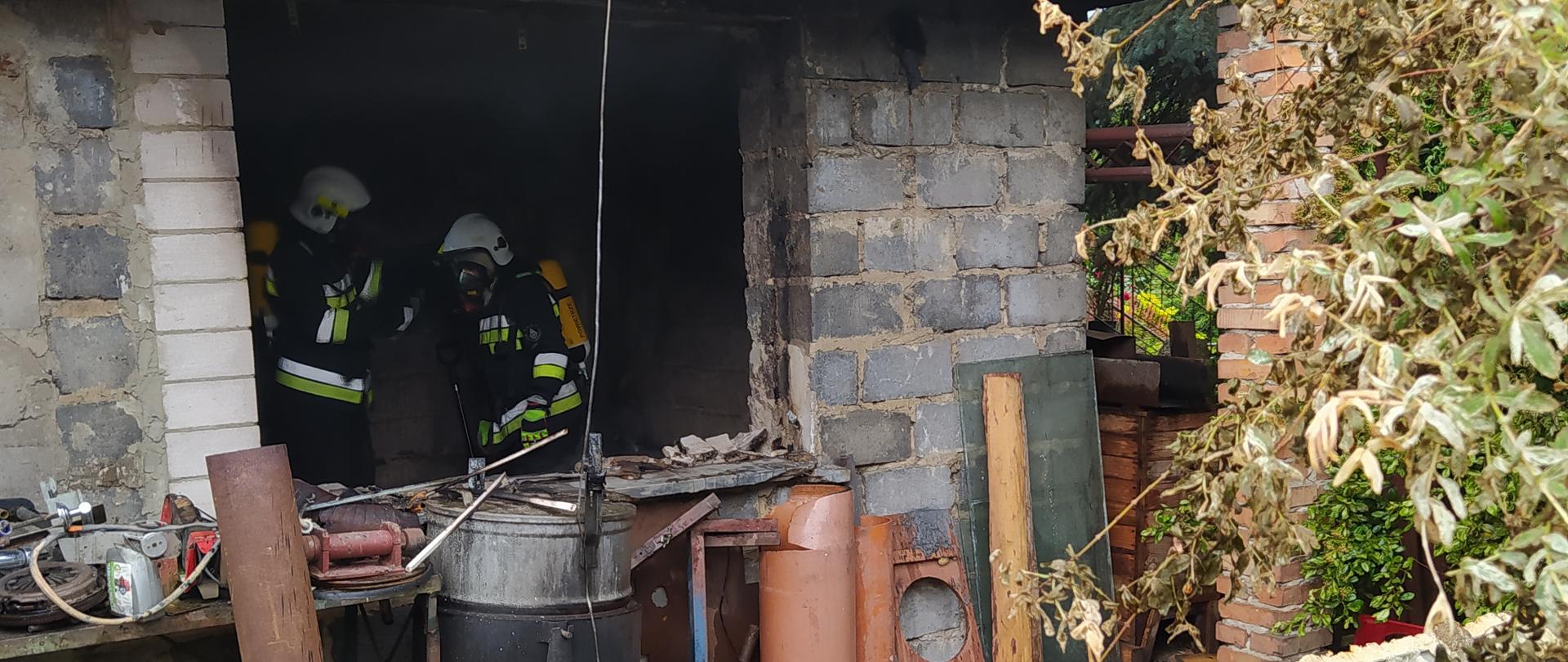 Strażacy w sprzęcie ochrony dróg oddechowych w pomieszczeniu.