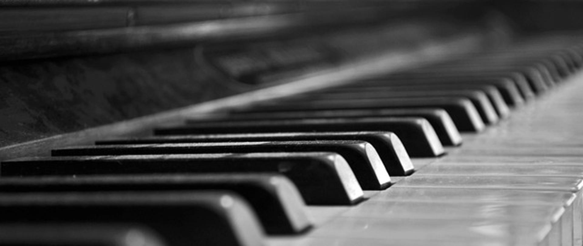 Zdjęcie przedstawia klawiaturę fortepianu w odcieniach szarości