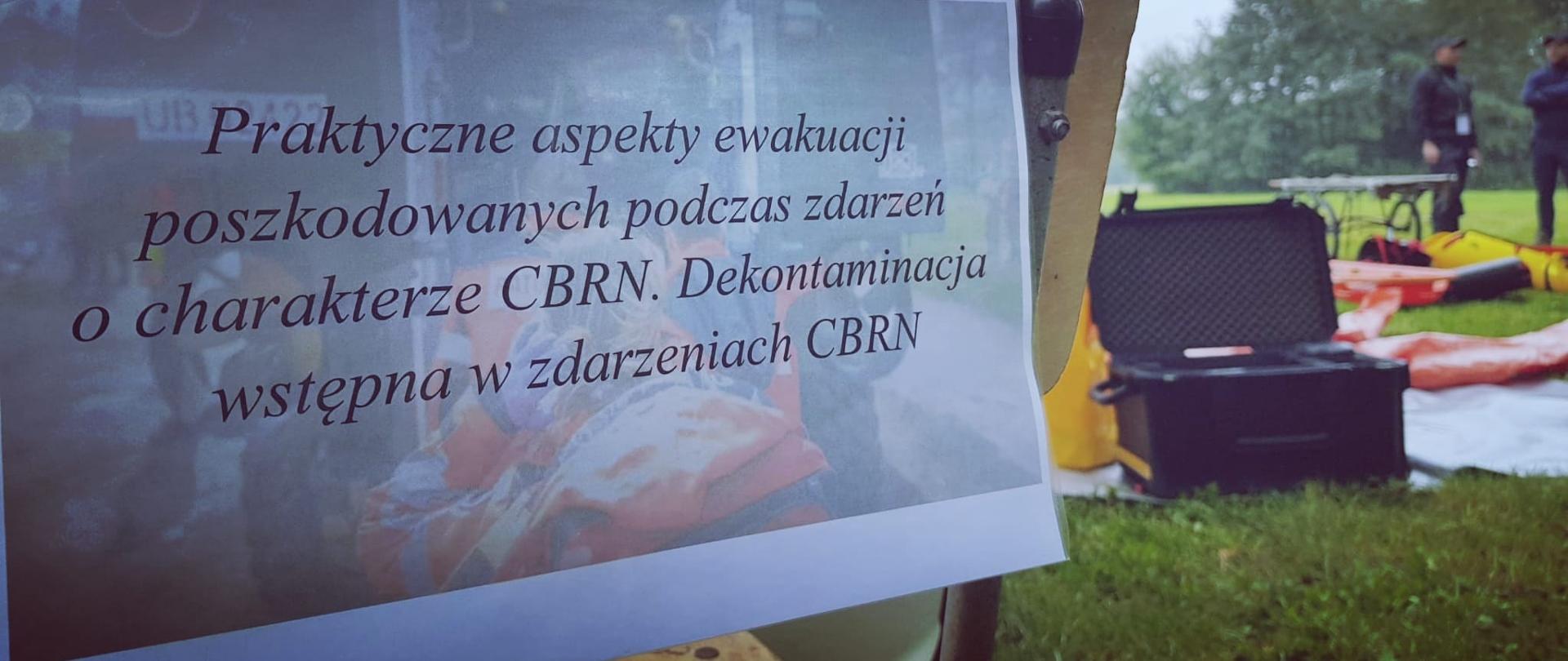 Na zdjęciu kartka z tematem panelu warsztatowego umieszczona na oparciu krzesła, w tle widoczny sprzęt ratowniczy