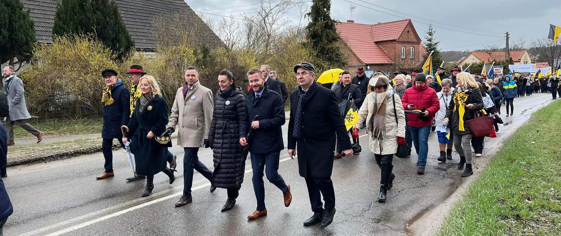 Grupa osób idąca ulica, część w ludowych strojach kaszubskich 