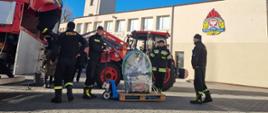 Strażacy ładują sprzęt na naczepę samochodu.