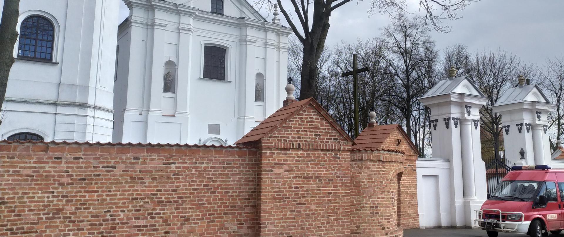 Samochód strażacki przed kościołem podczas akcji dystrybucji płynu dezynfekcyjnego do parafii powiatu bielskiego.