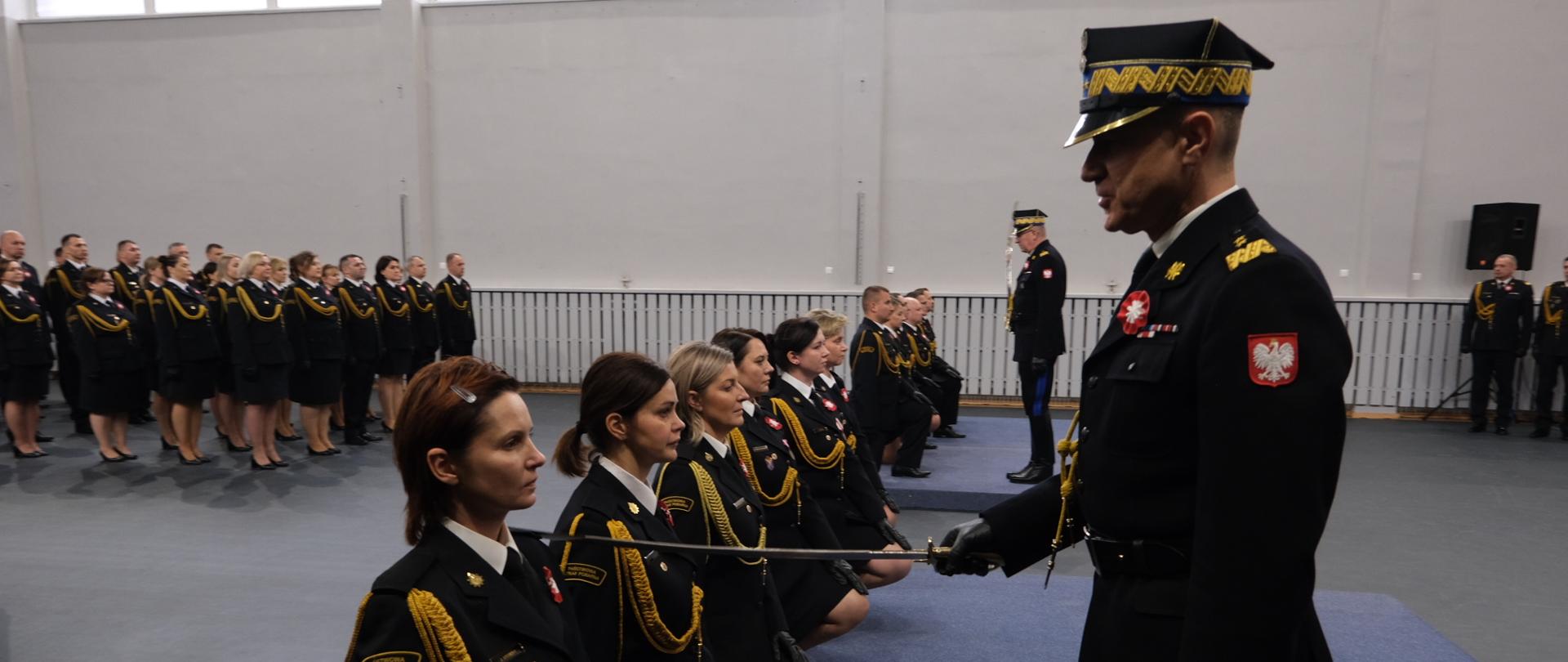 Komendant główny PSP wraz z zastępcą dokonują szablą uroczystej promocji funkcjonariuszy, przykładając ją do lewego ramienia strażaka