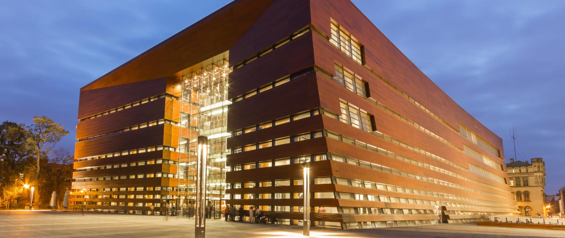 Zdjęcie przedstawiające gmach Narodowego Forum Muzyki we Wrocławiu uwiecznione w porze wieczorowej.