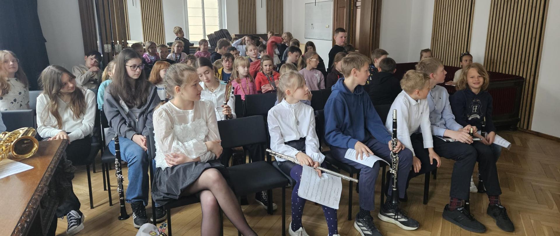 Galeria 20 zdjęć z audycji muzycznych, które odbyły się w Państwowej Szkole Muzycznej I st. w Kłodzku uczniowie grają na instrumentach na scenie sali koncertowej
