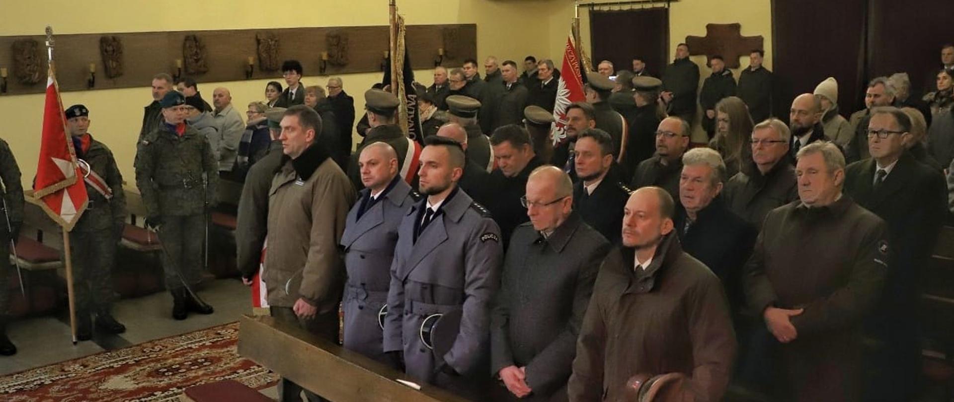 W kościele stoi kilkadziesiąt osób. W śród nich, funkcjonariusze w mundurach i poczty sztandarowe.