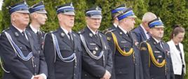 Przedstawiciele druhów Ochotniczych Straży Pożarnych oraz Komendanci powiatowi Państwowej Straży Pożarnej stoją w rzędzie na placu jednostki ratowniczo-gaśniczej, podczas oficjalnej uroczystości obchodów dnia strażaka w Rypinie