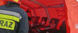 Poszkodowane dzieci na łózkach polowych w pomarańczowym namiocie ratowniczym