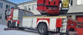 Zdjęcie przedstawia fabrycznie nową drabinę o wysokości 41,5 m, na tle garaży Jednostki Ratowniczo Gaśniczej w Zgierzu.
