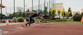 Na zdjęciu widocznych jest dwóch zawodników w trakcie startu podczas konkurencji pożarniczy tor przeszkód - 100 m.