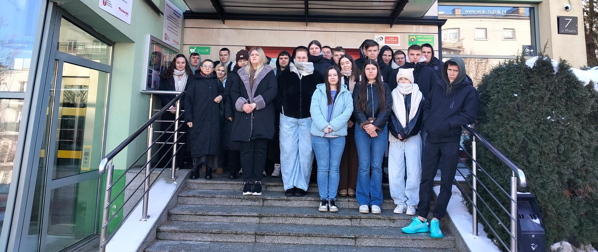 Grupa młodzieży na schodach budynku wraz z opiekunkami