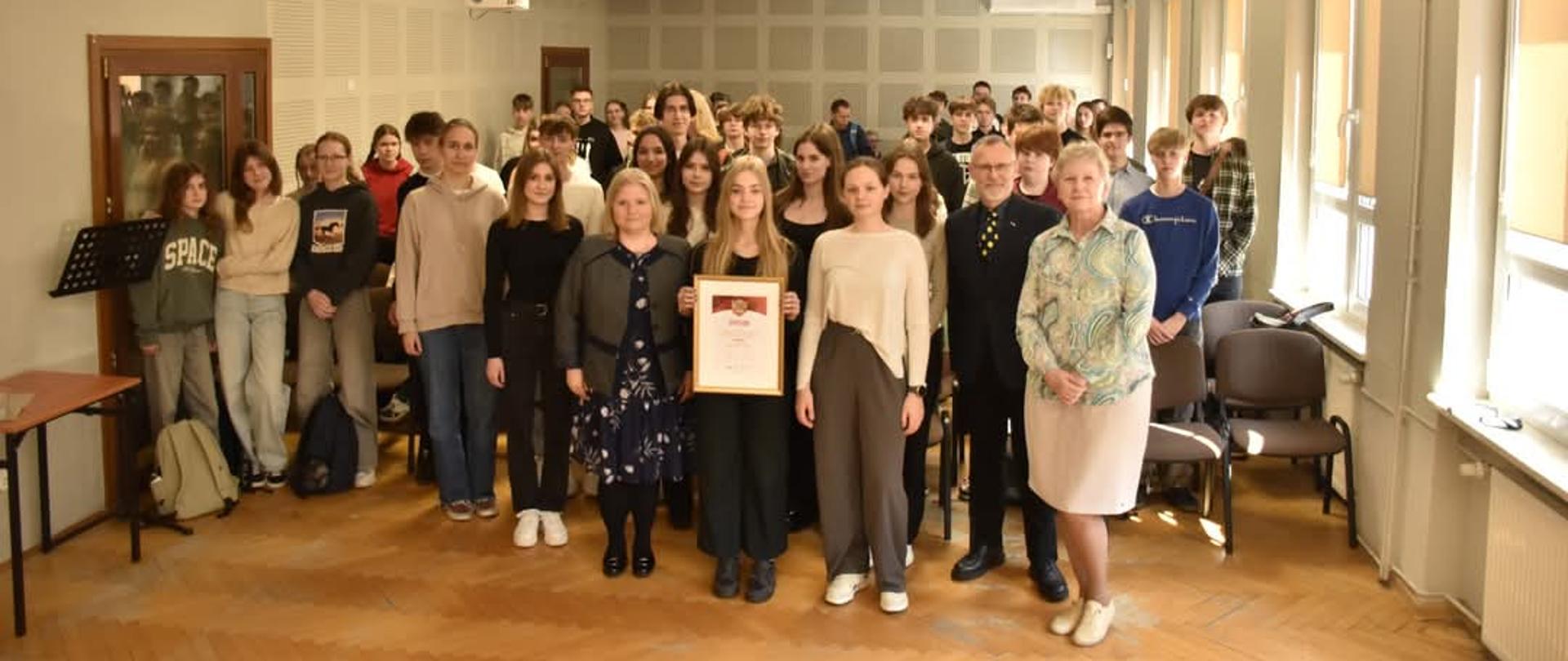 na zdjęciu stojąca grupa osób z dyplomem 