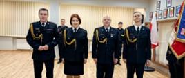 Zdjęcie przedstawia strażaków w trakcie uroczystego apelu wręczenia awansów.
W tle pomieszczenie - świetlica.
