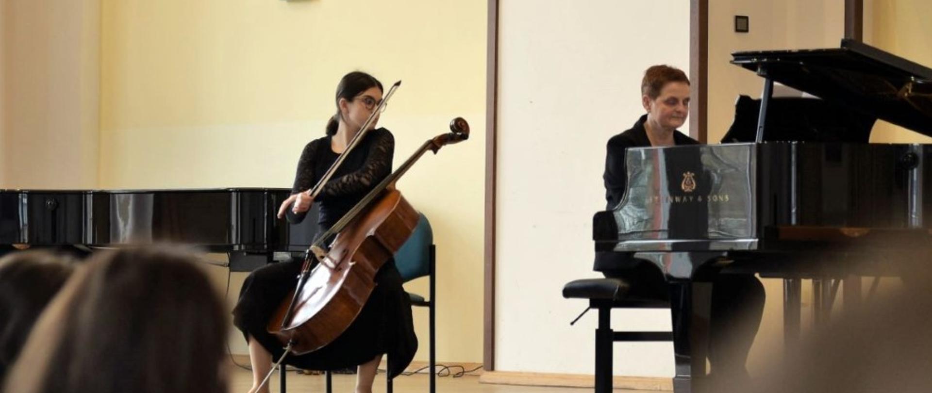 Zdjęcie kolorowe. Na scenie wiolonczelistka w czarnym stroju wraz z akompaniatorką grającą na fortepianie. 