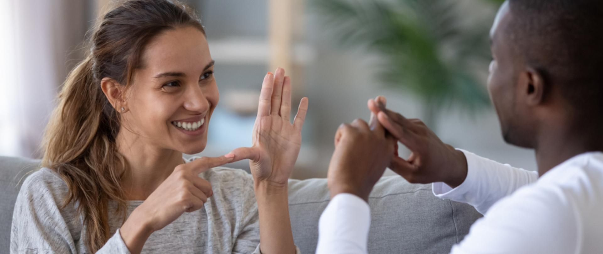 Dwie osoby rozmawiające w języku migowym.