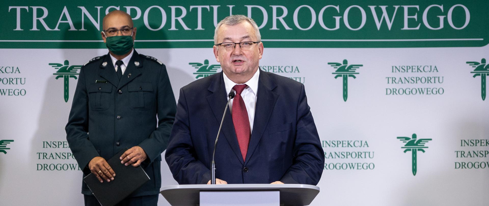 Minister infrastruktury Andrzej Adamczyk w siedzibie Generalnego Inspektoratu Transportu Drogowego w trakcie briefingu prasowego dotyczącego bezpieczeństwa w okresie ferii zimowych. Z tyłu Generalny Inspektor Transportu Drogowego Alvin Gajadhur